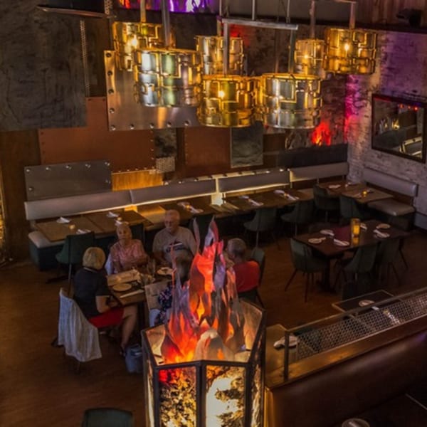 Overhead view of LYNQ restaurant with diners, modern lighting, and a fiery decorative centerpiece.