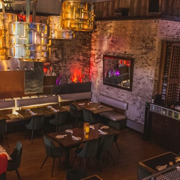 LYNQ restaurant interior with modern lighting, dark tables, banquettes, and a decorative fireplace.